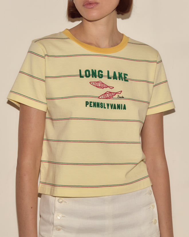 Woman wearing the Summertime Stripe Tee with yellow stripes, "Long Lake Pennsylvania" text, and fish graphics—perfect for capturing summer camp vibes.