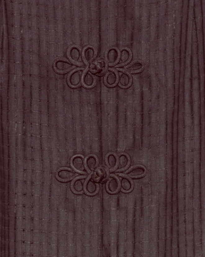 Close-up of two decorative knotted frog closures on textured dark brown fabric enhances the intricate detail of the Surrey Fringe Shirt.