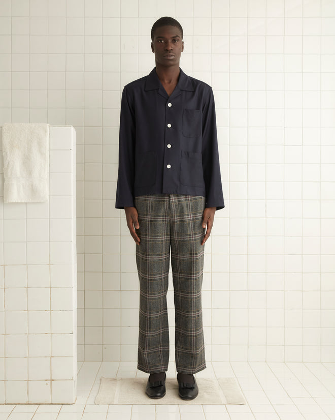 A person in the Swallowtail Overshirt - M and handmade plaid pants stands in a tiled room with a towel hanging nearby.