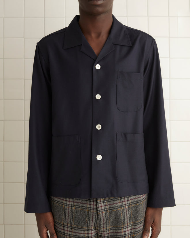 A person in the Swallowtail Overshirt - M and handmade plaid pants stands in a tiled room with a towel hanging nearby.