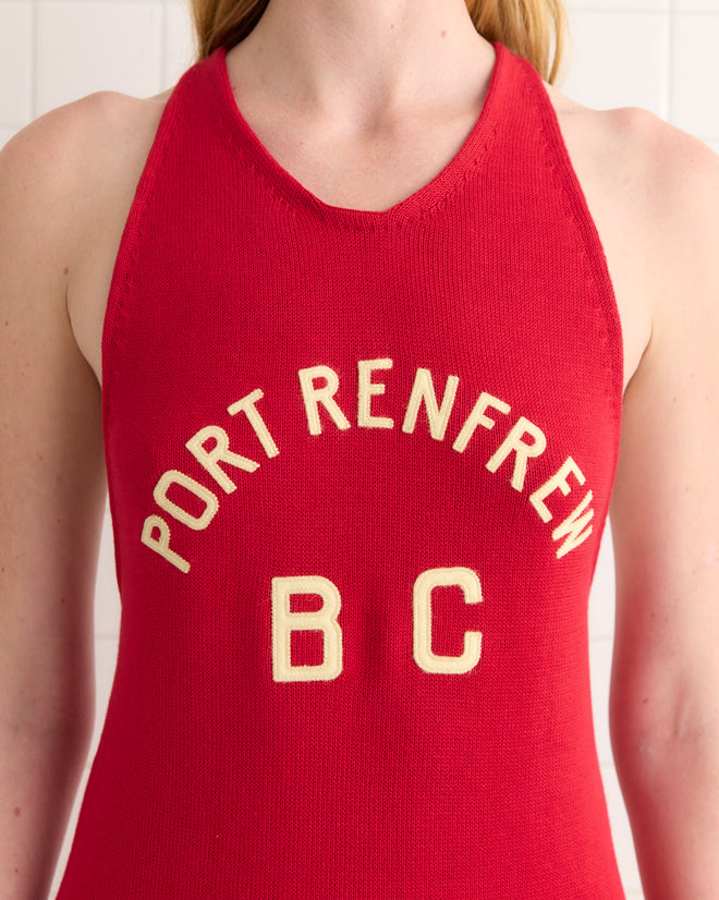 A person wears the Port Dress—a red tank top inspired by 1900s-1920s rowing singlets, featuring "Port Renfrew B C" in white on the front.