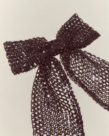 The Tanglenet Bow Barrette features a handmade black mesh bow adorned with silver sequins, neatly tied and styled for an elegant, 1930s-inspired look against a simple light background.