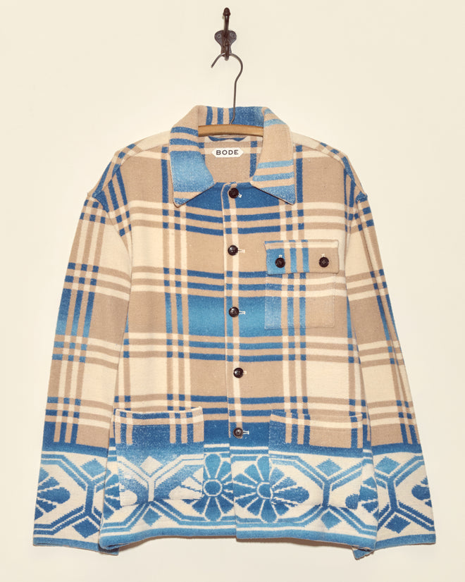 The Tartan Floral Jacket - S/M features unique brown and blue plaid with floral geometric patterns and black buttons, inspired by midcentury wool jacket styles, shown hanging on a hook.