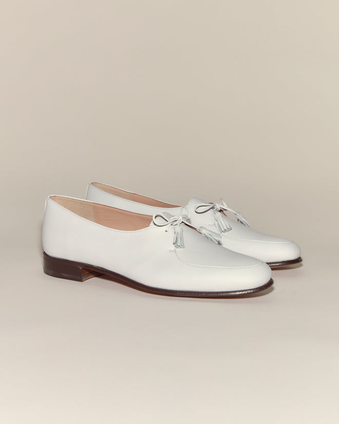 Tassel Shoes - White: Vintage-inspired white leather loafers featuring tasseled ties and brown soles, showcased against a neutral background.
