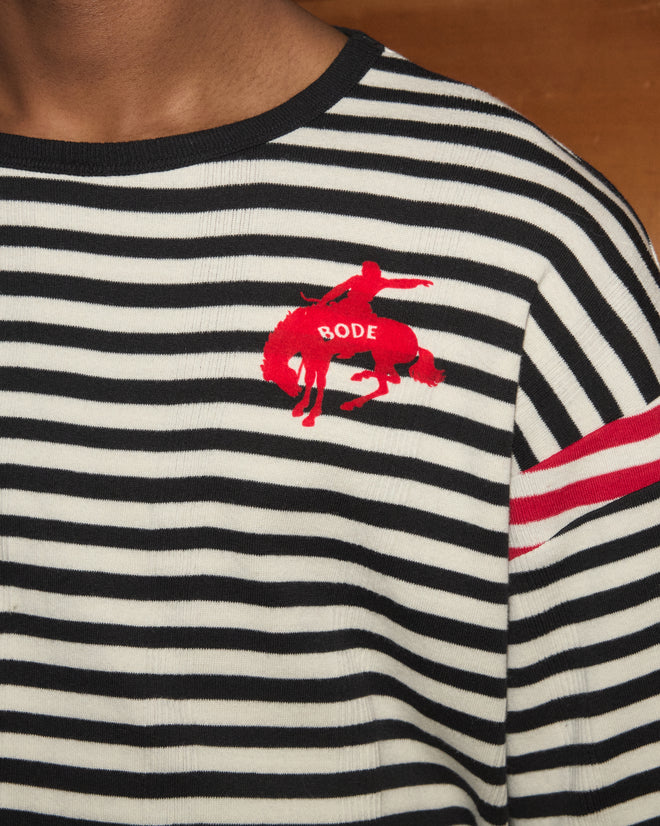 Rib Stripe Training Shirt: A black and white striped ribbed cotton tee featuring a bold red BODE logo and horse graphic on the chest, a vivid red stripe accenting the sleeve, and subtle rodeo rider details—a modern interpretation of classic 1980s jersey style.