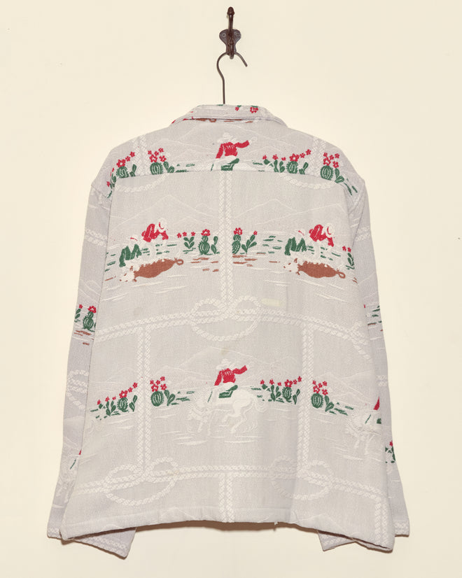 The Team Ropers Overshirt - XL is a unique white vintage cowboy shirt with playful cowboy, horse, and cactus patterns, stylishly showcased on a wall hook.
