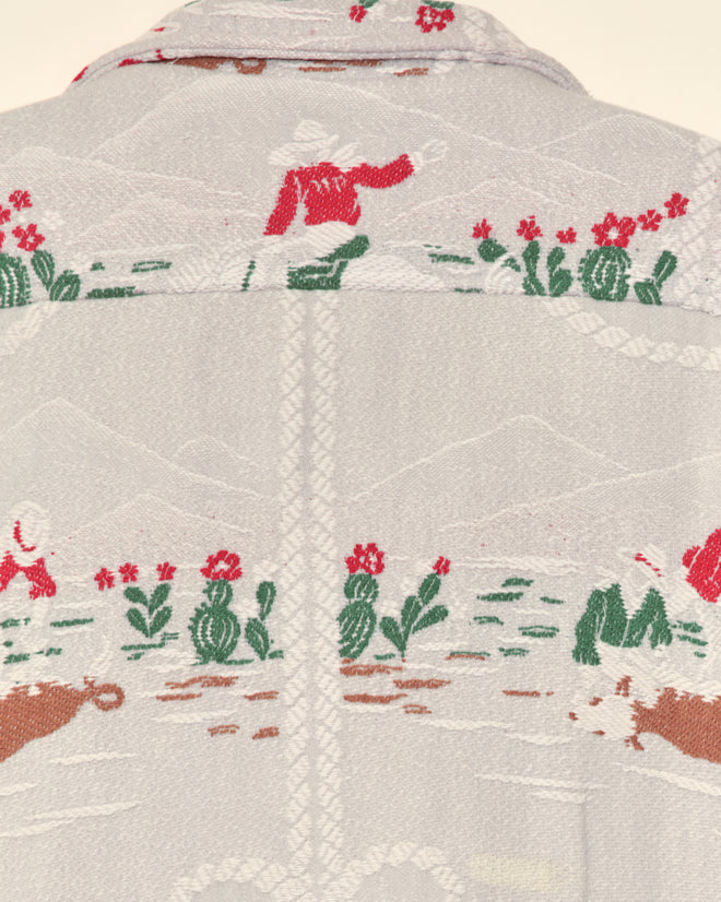 Close-up of the Team Ropers Overshirt - XL, a woven jacquard shirt with cowboys, cacti, and mountains in red, green, and brown on a light background—unique vintage western style.