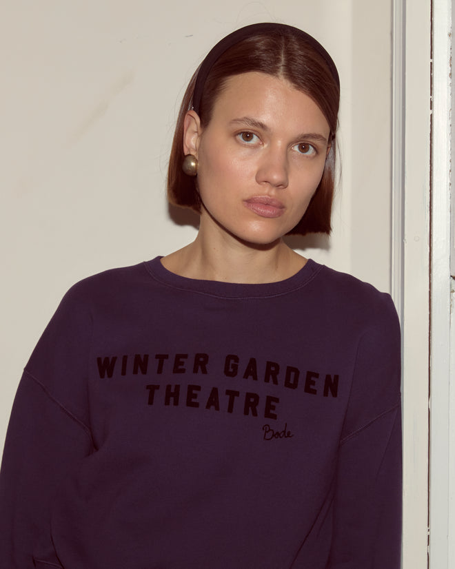 Woman with short brown hair and a headband, wearing the Theatre Crewneck - Dark Purple.