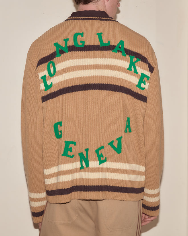 Person wearing a Timber Stripe Cardigan, featuring brown stripes and green "LONG LAKE GENEVA" lettering on the back, inspired by classic Poconos summer camp style.