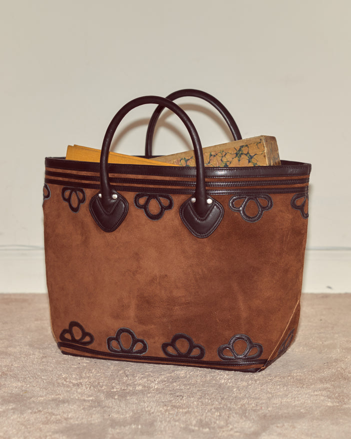 Brown tote bag made from soft suede in a boxy silhouette. It is embellished with looping leather appliquéwork.