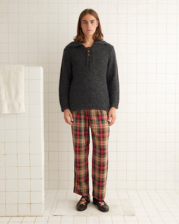 A person wearing a dark sweater and Truro Plaid Trousers made from plaid deadstock fabric with a hand in their pocket.