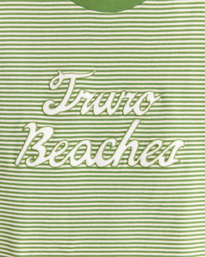 The Truro Stripe Cropped Tee is a 1950s vintage-inspired shirt made of green and white striped fabric, embroidered with "Truro Beaches" in elegant white cursive.