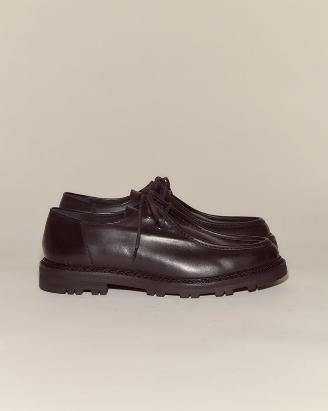 A pair of University Shoes - Black, crafted from Napa leather with thick soles, displayed against a plain beige background.