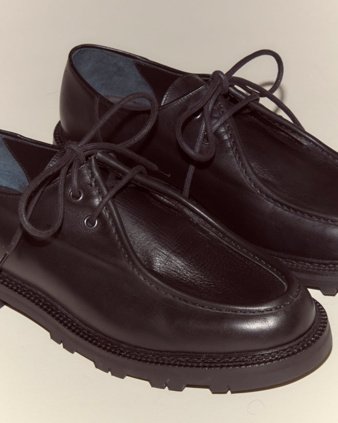 A pair of University Shoes - Black made from Napa leather with laces and thick, ridged rubber soles displayed on a neutral background.