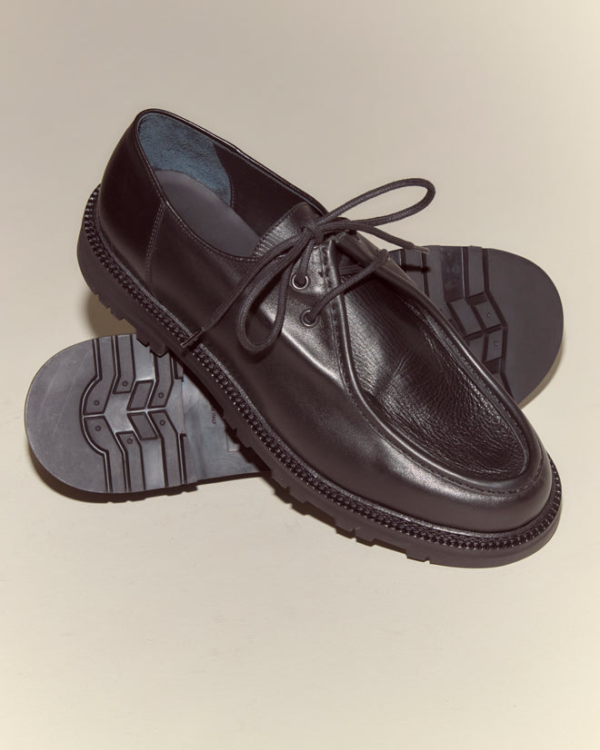 University Shoes - Black: Classic Italian Napa leather lace-ups with textured rubber soles. One shoe is upright while the other displays the sole, showcasing stylish design and durability.