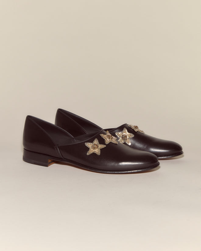 The Bullion Star Shoes feature black Napa leather and sequined star embellishments on the uppers, photographed on a neutral background to evoke the timeless charm of an Italian house shoe.