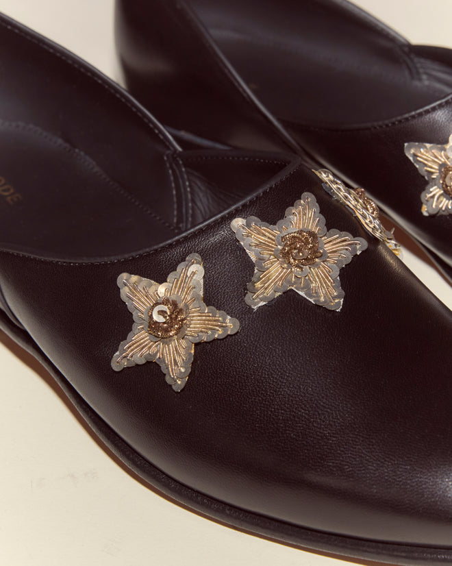 The Bullion Star Shoes are crafted from black Napa leather and feature bold sequined stars with gold star-shaped accents on the front, adding a glamorous touch to these Italian house shoes.