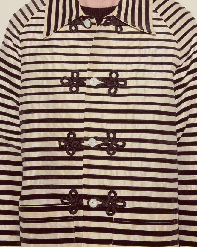 Person wearing the Velvet Bannister Jacket, featuring black and white stripes, decorative buttons, black frog closures, and a large collar.