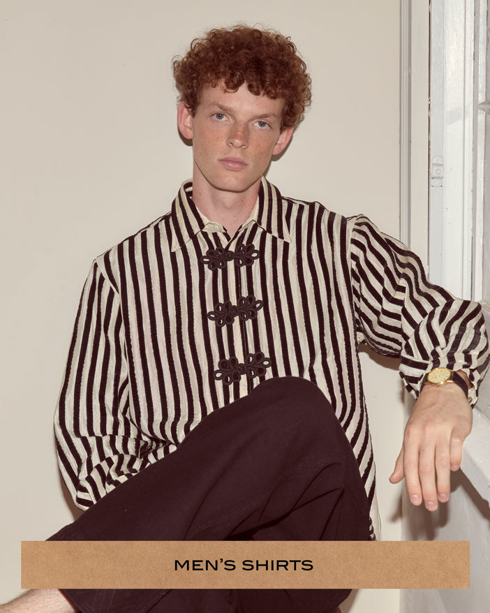 Cream shirt patterned with rows of black hand-applied velvet ribbon and frog closures