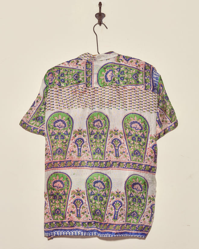 The Verdigris Print Shirt - XXL, crafted from vibrant vintage sari fabric, hangs on a hook against a plain wall.