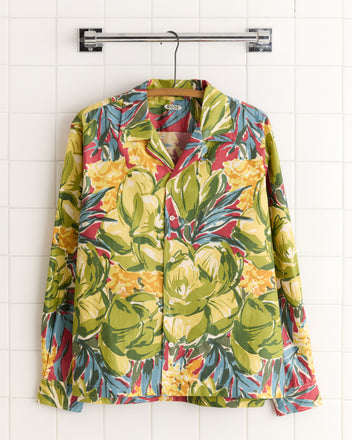 The Watercolor Foliage Long Sleeve Shirt - L, featuring an oversized botanical print in yellow, green, and red, hangs on a hanger.