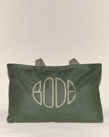 The Waxed Cotton Zip Tote - Green features gray handles and a bold, stylized embroidered Bode logo on the front. Crafted in Italy from green waxed cotton.