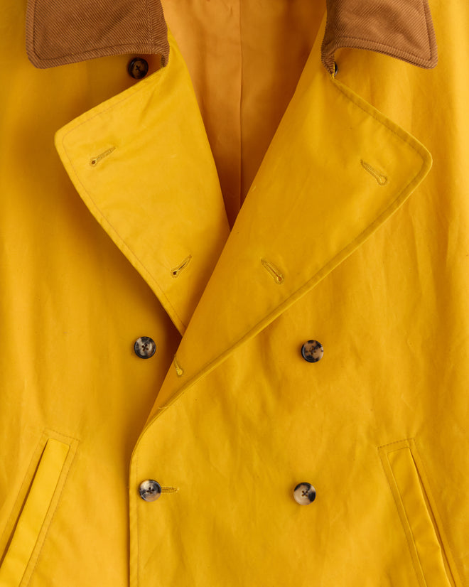 Close-up of the Waxed Peacoat - Yellow, a double-breasted French style featuring a brown collar and dark buttons.