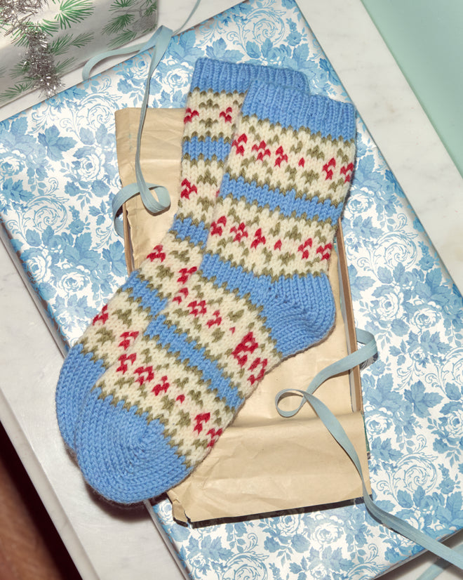 Wedgewood Socks—featuring blue, white, and red vintage-inspired patterns—are displayed on wrapped paper inside a decorative blue floral gift box.