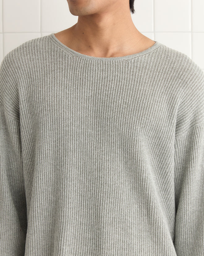 A person wearing the lightweight Weymouth Sweater, ideal for cool days, stands against a white tiled background.