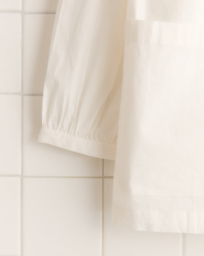 The White Smock Shirt stands out against the tiled wall background.