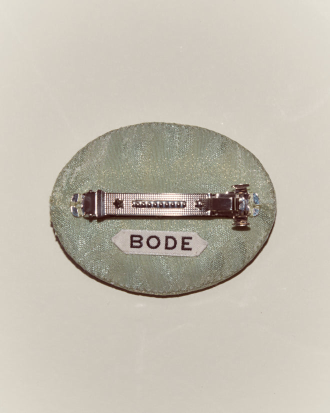 The Willow Barrette - Green is a round green fabric pin with a metal clasp and a white "BODE" label, ideal for Peter Pan costumes, shown on a neutral background.