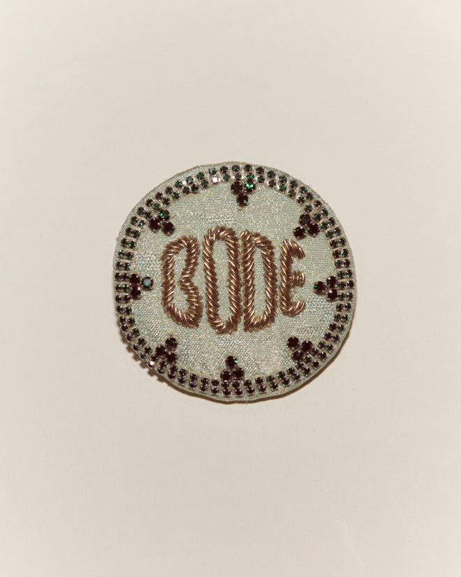 The Willow Brooch - Green features intricate embroidery, gold "BODE" lettering, beads, and sequins—an eye-catching accessory that elevates any look and pairs perfectly with other Bode pieces.