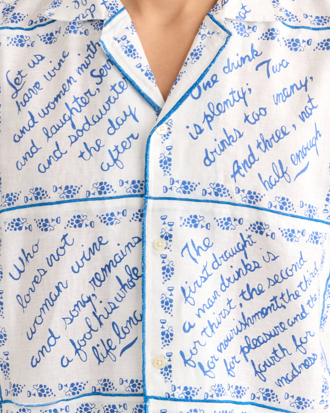 The Wine Poems Short Sleeve Shirt is a white linen shirt with blue handwritten text, blue piping, and quotes in cursive and block lettering.