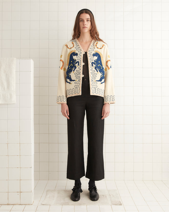 A person wearing the Winter Stallion Jacket and black pants stands against a tiled wall in a minimalistic setting.