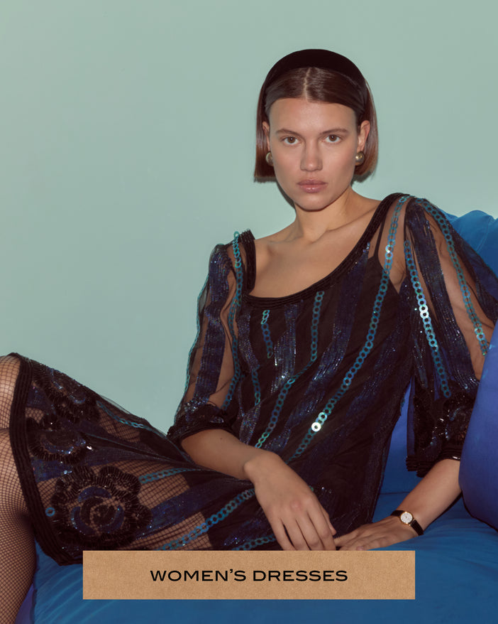 Model wearing a blue sequin dress on a blue couch.