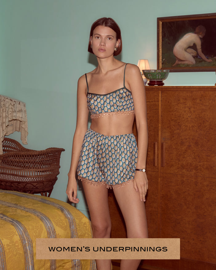 Model wearing a matching top and bottom patterned set in a bedroom.
