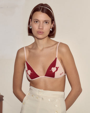 A woman wears the Wonderland Bra with high-waisted cream pants indoors, her whimsical style echoing Alice Through the Looking Glass.