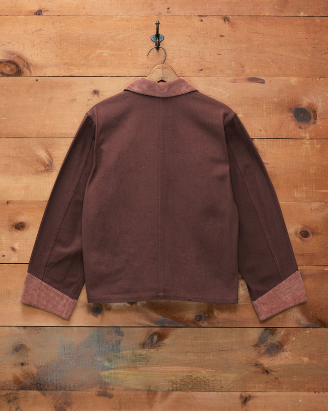 Craft Jacket - Brown cotton twill workwear jacket featuring corduroy trim on the collar and cuffs, displayed hanging on a hook against a wooden wall background.