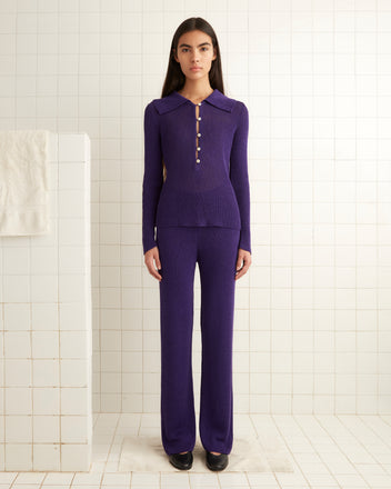 A person wearing the Quincy Joggers in purple stands in a tiled room with a white towel hanging nearby.