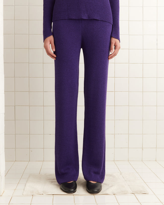 Someone is wearing Quincy Joggers - Purple, evoking 1970s style, paired with black shoes on a white tiled floor.