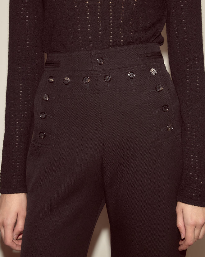 Person wearing Riding Twill Sailor Trousers in black, featuring a high-waisted 1940s Navy-inspired design with multiple buttons, paired with a black long-sleeve top.