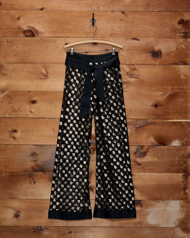 Pyrite Sequin Pants in black with metallic flower-shaped sequins and a wide ribbon tie.