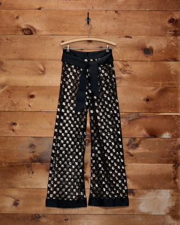 Pyrite Sequin Pants in black with metallic flower-shaped sequins and a wide ribbon tie.
