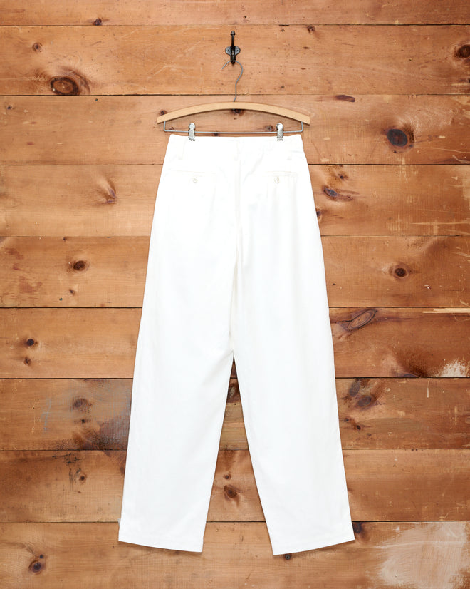 Button Jar Trousers, featuring a white high-waisted wide-leg design, hanging on a wooden hanger against a rustic wooden wall background.