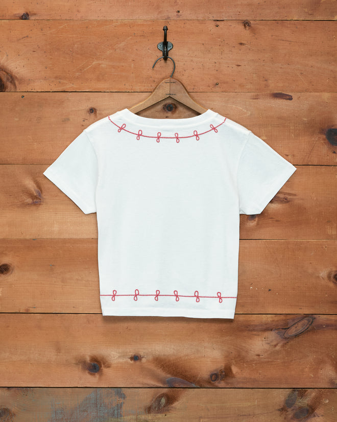 Lasso Tee: A white short-sleeve T-shirt made in Portugal from 100% cotton, displayed on a wooden hanger and featuring pink looped couching embroidery along the top and bottom edges.