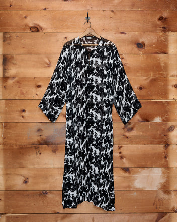 Appaloosa Kaftan in a black and white pattern hangs on a hook against a wooden wall.