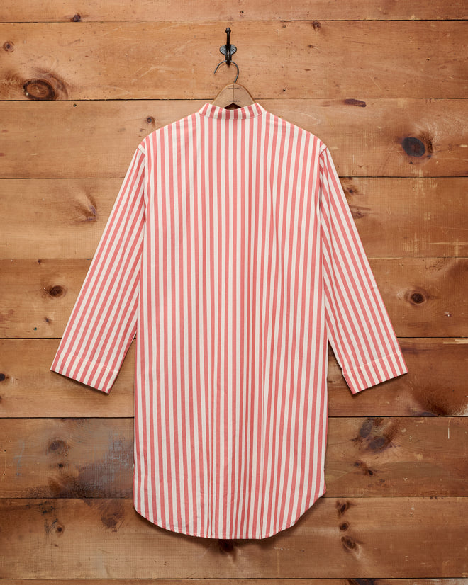 Rancho Tunic in red and white vertical stripes, inspired by classic shirting and crafted from 100% cotton, hanging on a wooden wall.