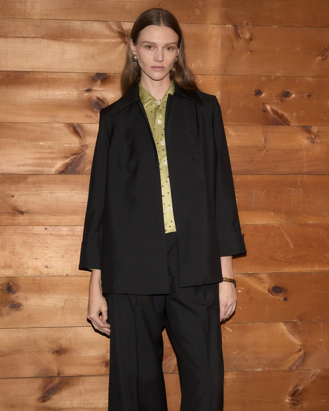 A person wearing a black Sonora Mohair Jacket over a light green collared shirt and black trousers.