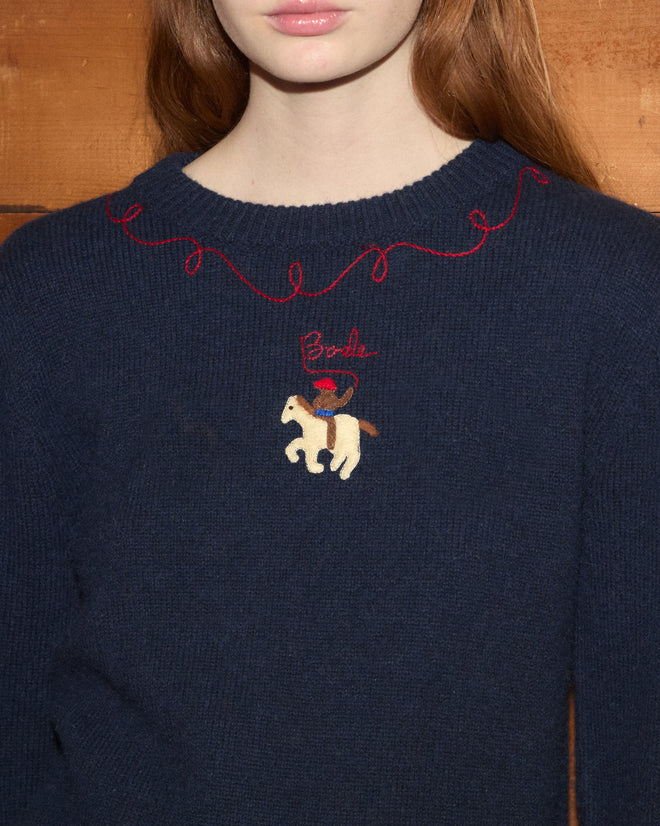 Woman in a navy Cowboy Appliqué Pullover with red trim and an embroidered horse and “Brenda” on the chest.