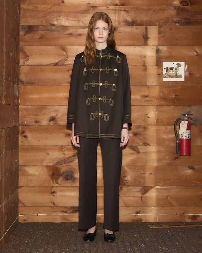 A model wearing a dark brown wool Cavalry Coat with bronze buttons and matching trousers.